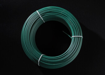 A coil of green PVC coated wire. Isolated on a black background.