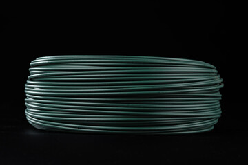 A coil of green PVC coated wire. Isolated on a black background.