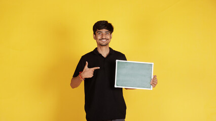 Man holding a blank board indoors, providing copy space for text or design mockups, with a casual...