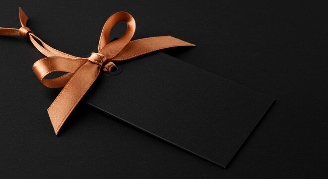 Dark gift box tied with a satin copper ribbon, elegant and simple.
