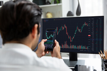 Trader businessman searching on smartphone, analyzing in dynamic stock exchange investment screen on pc with invest highest profitable financial technology market at modern home office. Surmise.