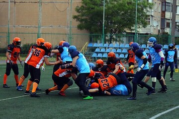 American football players in black and orange uniforms pile on players in black and orange uniforms...