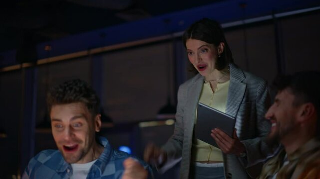 Night winner looking laptop rejoicing success with colleagues workspace portrait