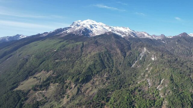 Drone view of Haba Snow Mountain with snowy peak on a sunny day with blue sky in China.