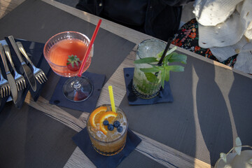 Cocktail glasses sitting at kitchen table - Amarretto sours, strawberry daquari and Mojito. Food and beverages.