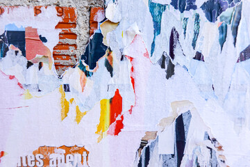 Billboard with old posters. Ripped torn posters texture background in city street. White, red, blue, yellow colors