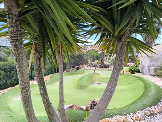 A cheerful mini golf course with bold colors and a large artificial tree centerpiece. On dinosaur minigolf in Portimao - Portugal – May 5 of 2025