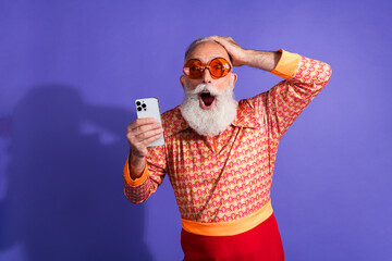 Vintage styled elderly man reacts with excitement while holding smartphone