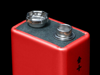 Close-up of a 9V battery displaying the positive terminal indicator on a black background