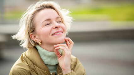 Happy Eastern European woman relaxing outdoors in sunny weather