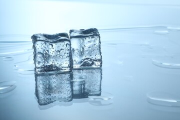 Cubes of clear ice on mirror surface, space for text