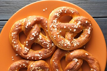 Tasty pretzels with salt on dark wooden table, top view