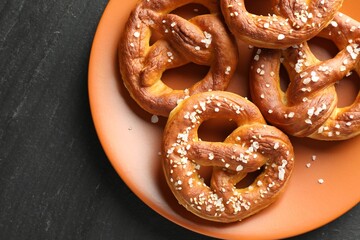 Tasty pretzels with salt on black table, top view. Space for text