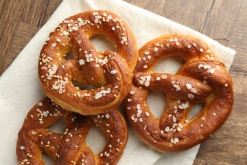 Tasty pretzels with salt on wooden table, flat lay
