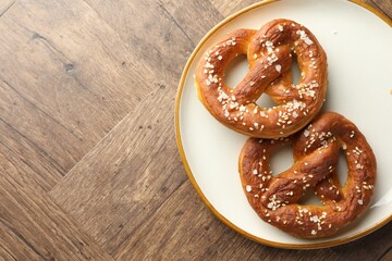 Tasty pretzels with salt on wooden table, top view. Space for text