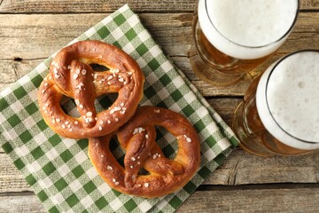 Tasty pretzels and glasses of beer on wooden table, flat lay
