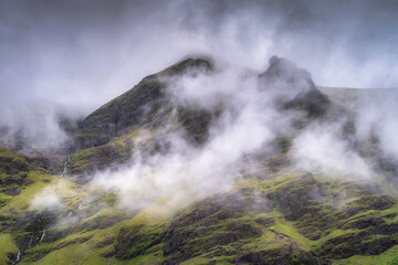Experience a breathtaking view of mist covered Carrauntoohil mountain, showcasing vibrant green slopes and an incredibly tranquil atmosphere, perfect for nature enthusiasts to enjoy, Kerry, Ireland