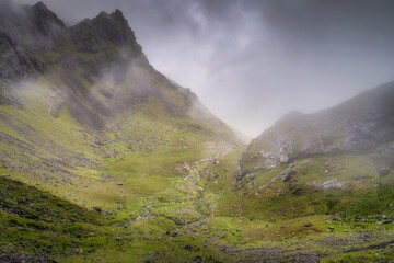 This stunning view of misty Carrauntoohil mountain highlights vibrant green valleys and rocky peaks, all wrapped in tranquil fog, ideal for outdoor enthusiasts and nature lovers, Kerry, Ireland