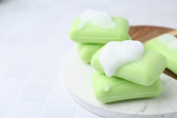 Soap bars with foam on white table, closeup. Space for text