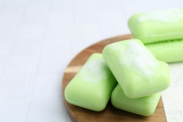 Soap bars with foam on white table, closeup. Space for text