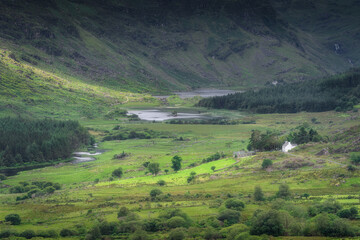 A breathtaking and stunning view showcases vibrant green of Black Valley and rolling hills, with a charming white cottage nestled peacefully in a tranquil landscape, Kerry, Ireland