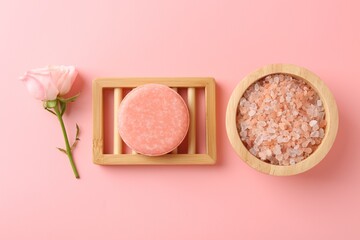 Soap bar, sea salt and beautiful rose on pink background, flat lay