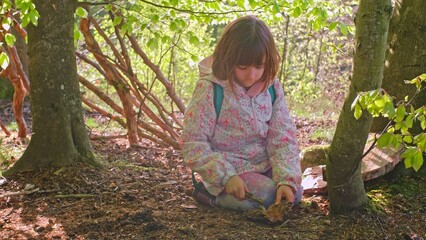 Smart Curious Caucasian Girl Playing in Forest with Piece of Wood Practicing Survival and Bushcraft Skills