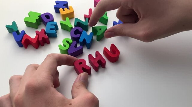 A young boy with dyslexia trying to spell a word with letters. Close up.