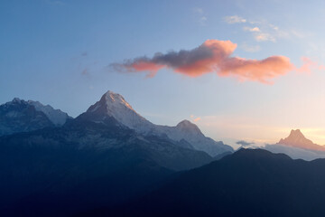 Stunning sunrise illuminates the South Annapurna mountain range from Poon Hill, revealing snow-capped peaks and soft clouds. The vibrant colors create a breathtaking landscape in the Himalayas.