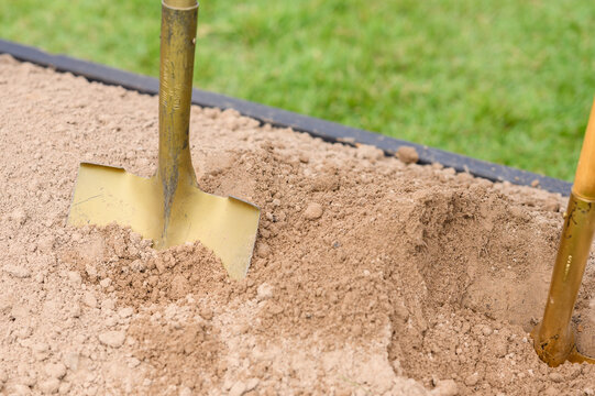 Groundbreaking Ceremony with Golden Shovels and White Hard Hats in Outdoor Setting