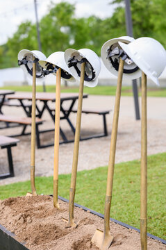 Groundbreaking Ceremony with Golden Shovels and White Hard Hats in Outdoor Setting