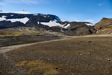 Iceland. Vast, barren land stretches across near Sn&aelig;fellsj&ouml;kull, featuring rocky terrain and snow-capped mountains. The sunlight illuminates the unique geological formations