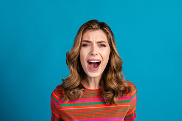 Young woman expressing emotion while posing against blue background, showcasing modern fashion in a...