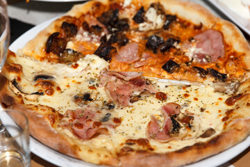 Freshly baked half-and-half pizza with creamy and tomato sauce toppings on plate.