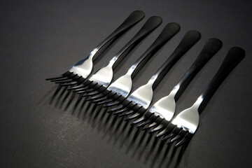 Close up shot of silver forks layered together side by side with dark background, Food conceptual image, Forks isolated 