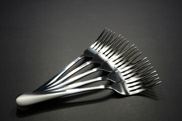 Close up shot of silver fork layered together side by side with dark background, Food conceptual image, Forks isolated 
