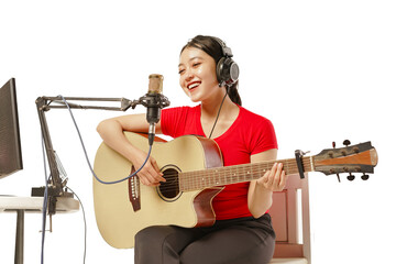 Beautiful Asian woman wearing headphones recording studio playing guitar with singing