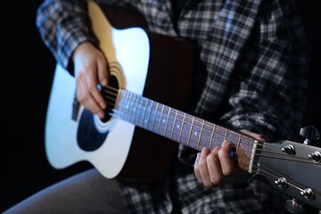Fototapeta premium Woman playing guitar on black background, closeup
