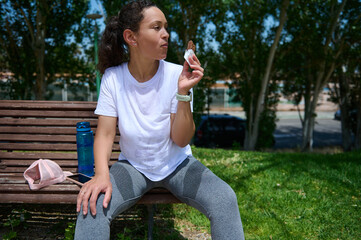 Woman Resting on Park Bench Enjoying a Snack After Outdoor Workout