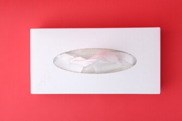 Box with paper handkerchiefs on red background, top view