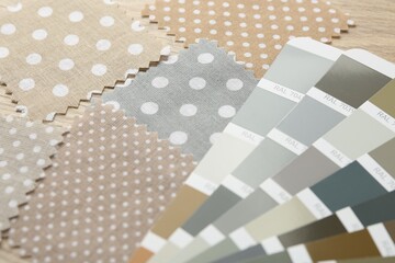 Samples of colorful fabrics and color palettes on wooden table, closeup