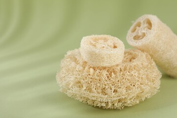 Different loofah sponges on olive background, closeup. Space for text