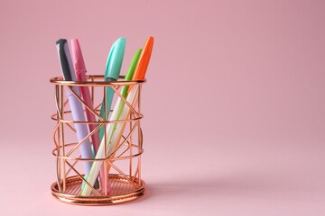 Different stationery in pen holder on pink background. Space for text
