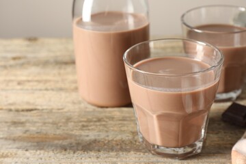 Tasty chocolate milk in glasses on wooden table, closeup. Space for text