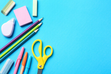 Pens and other stationery on light blue background, flat lay. Space for text