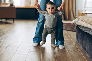 Portrait of baby carefully walking with the mother gentle support at home