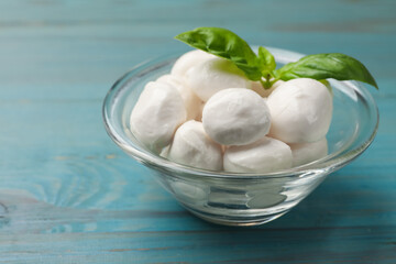 Mozzarella cheese balls and basil on blue wooden table, closeup