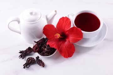 Tasty hibiscus tea, dry roselle sepals and beautiful flower on white table