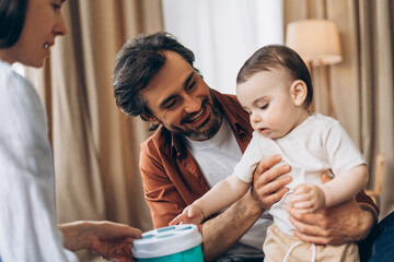 Smiling parents enjoying playtime with their infant son at home