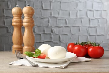 Tasty mozzarella cheese balls, tomatoes and basil on wooden table